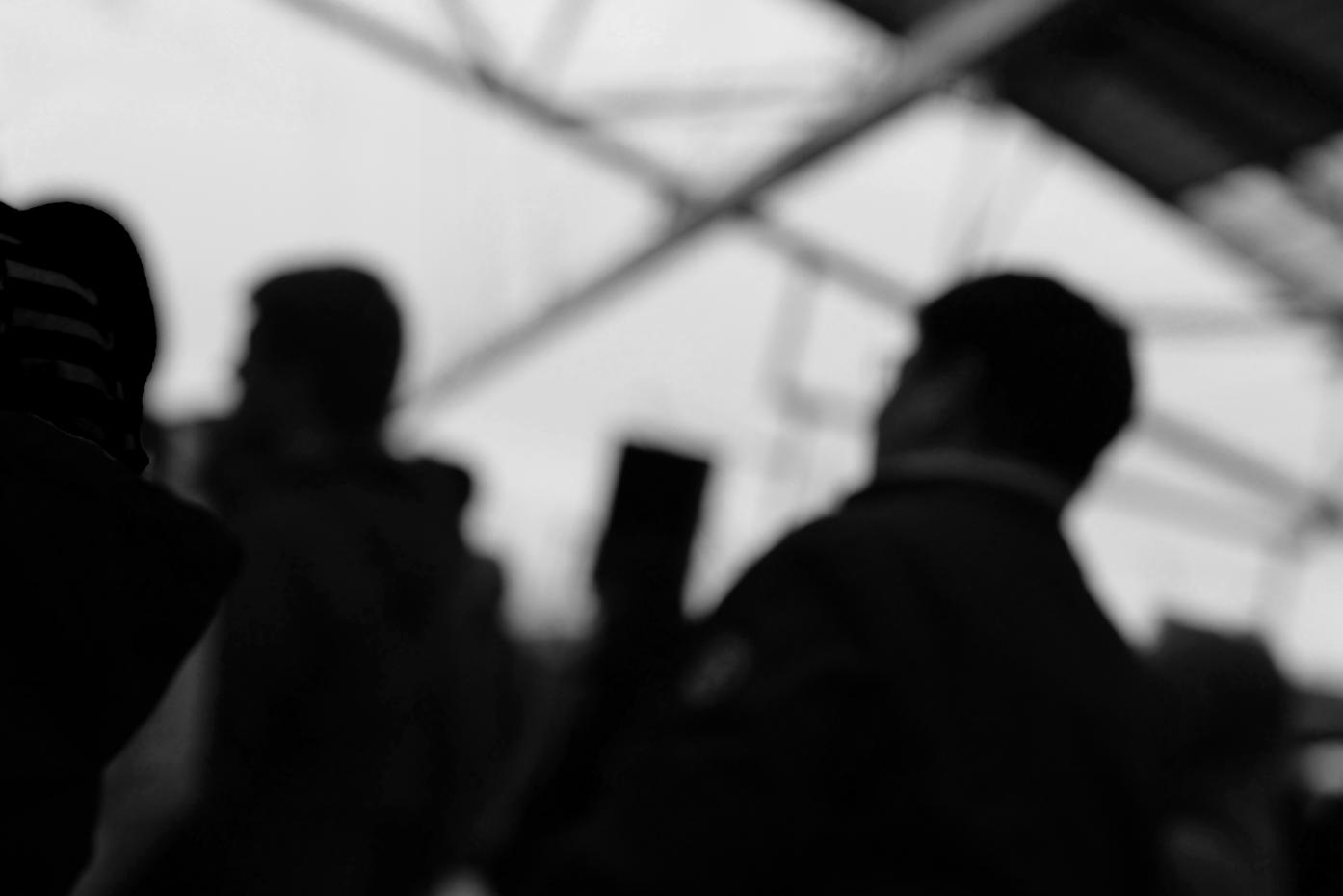 Das Schwarzweißfoto zeigt Umrisse von Menschen vor hellem Hintergrund