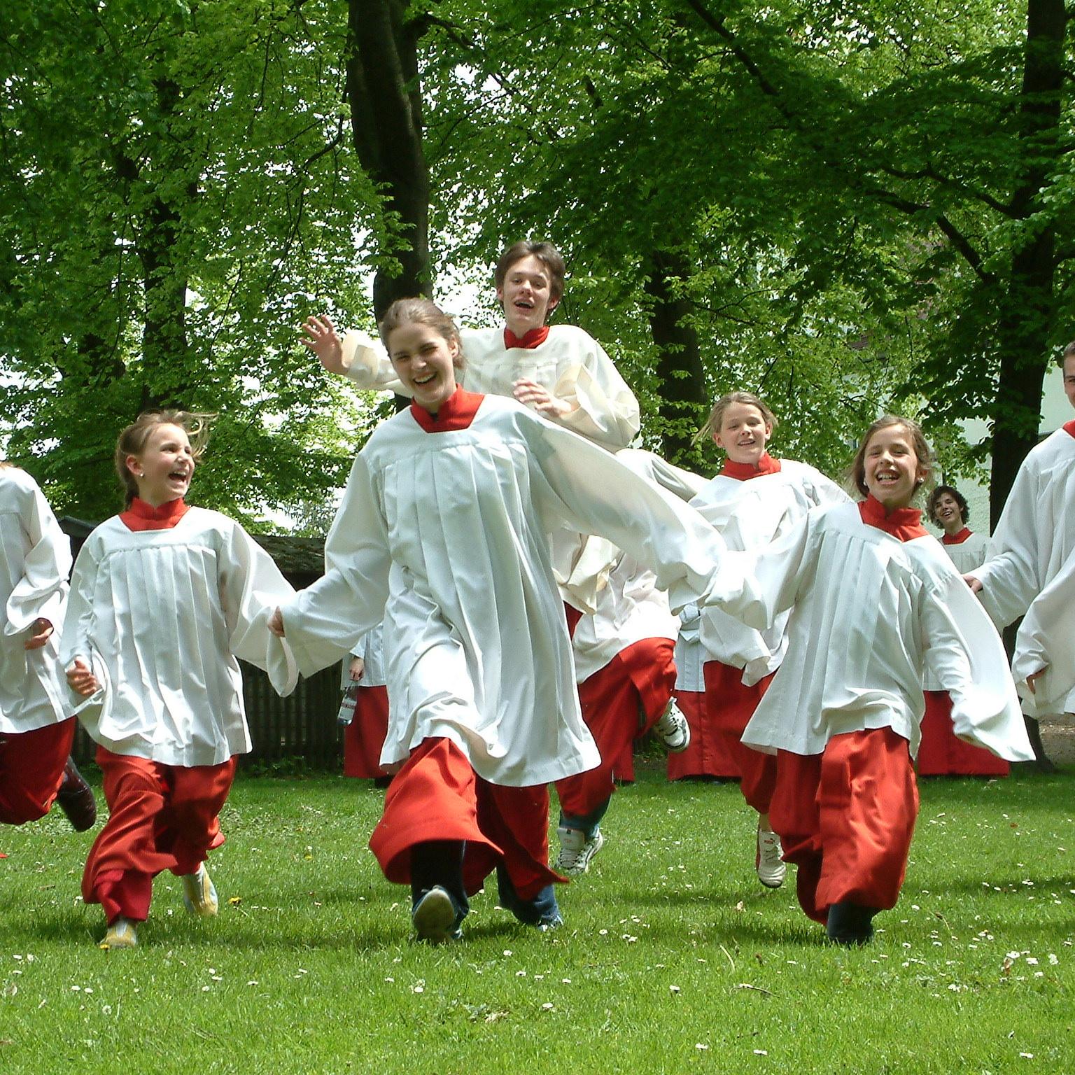 in einem Park laufen acht Messdienerinnen in rot weißen Gewändern auf uns Bildbetrachterinnen zu (c) Markus Grimm in Pfarrbriefservice in einem Park laufen acht Messdienerinnen in rot weißen Gewändern auf uns Bildbetrachterinnen zu