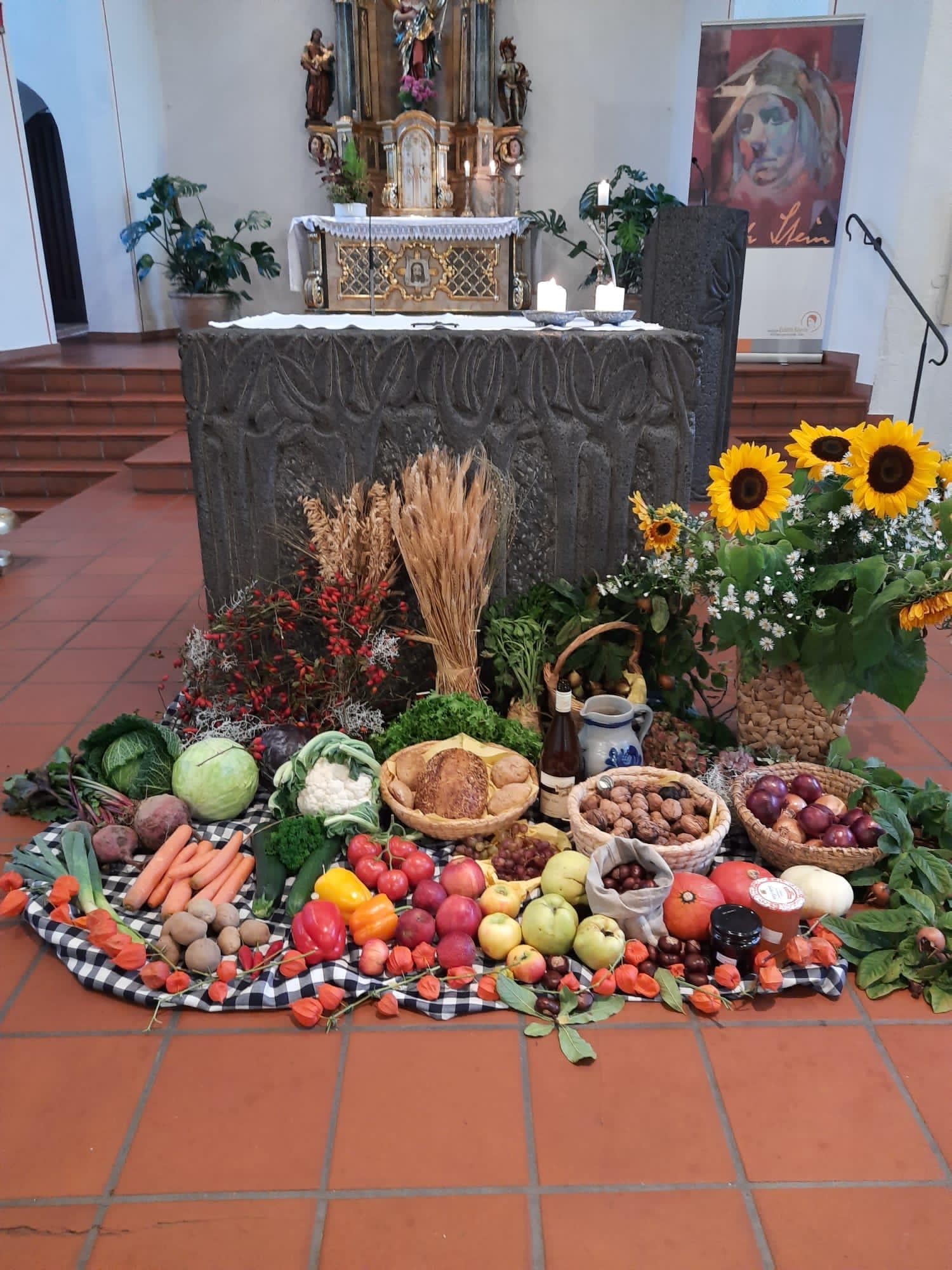 Vor dem Altar liegen verschiedene Gemüse und Obstsorten, Nüsse und Sonnenblumen, Wein und Getreideähren