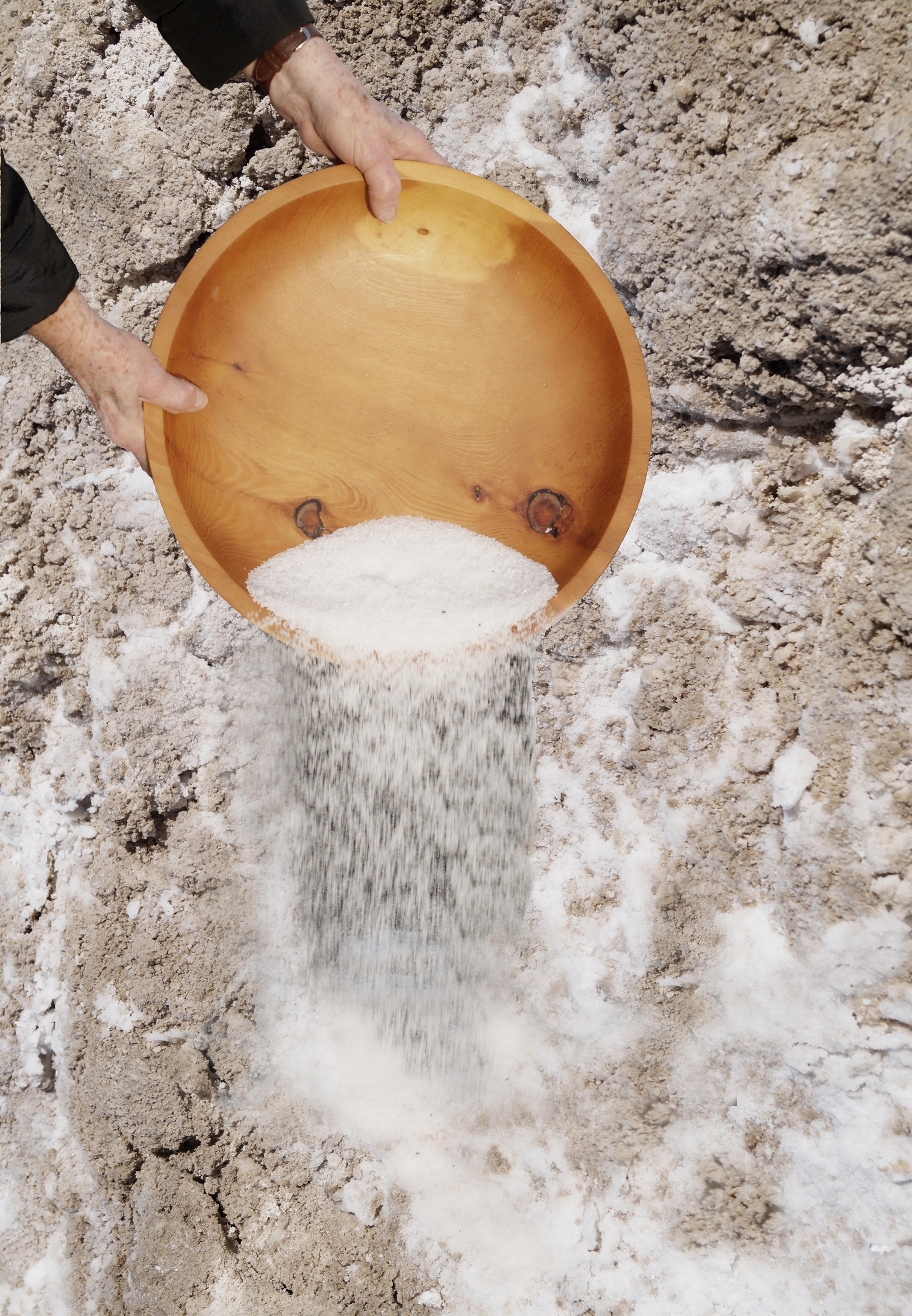 Salz wird aus einer Holzschüssel auf die Erde gestreut